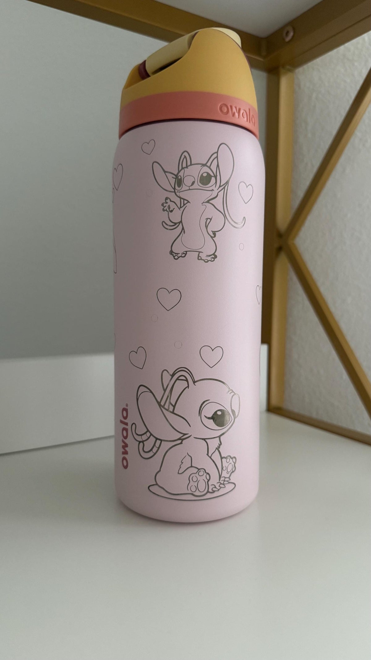 Side view of a light pink Owala with engraved Angel and Stitch-inspired art
