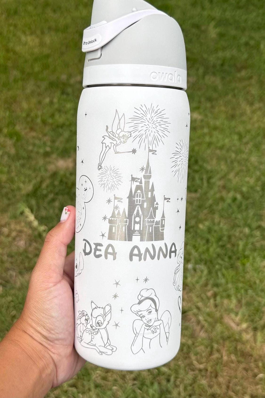 White Owala FreeSip laser engraved with a Disney-inspired castle, characters and the name Dea Anna