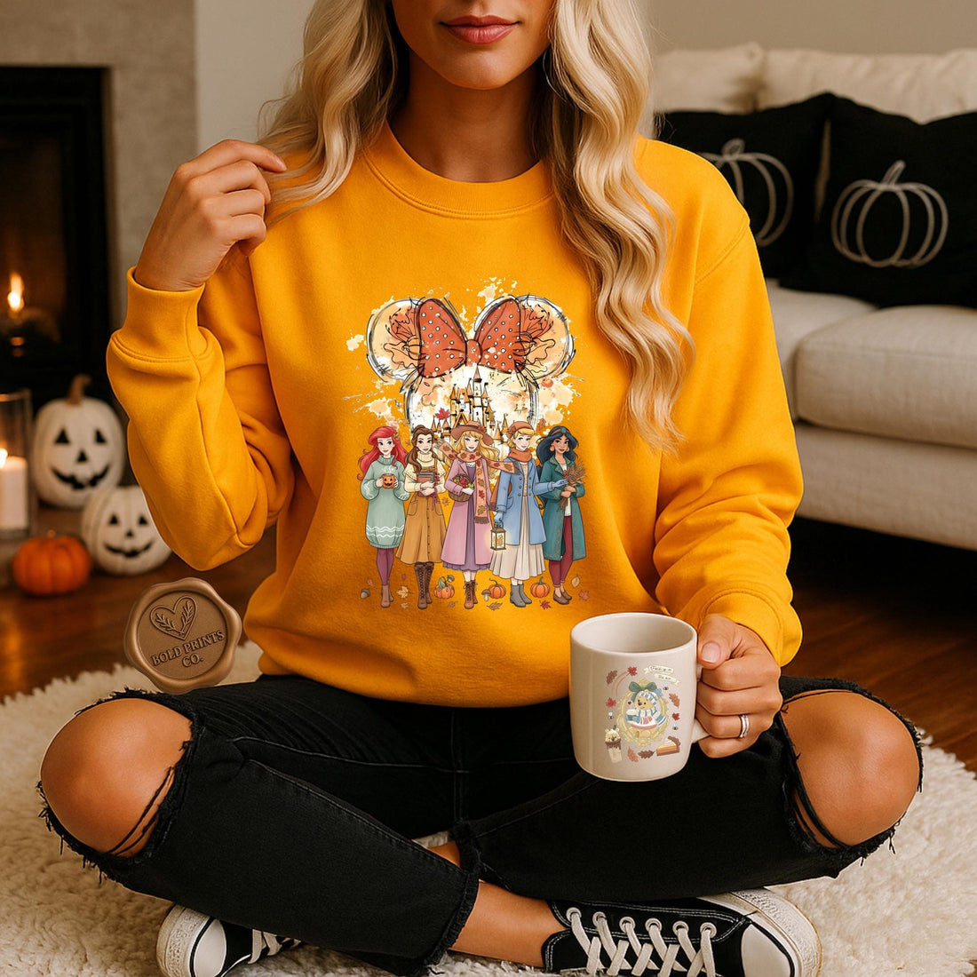 Woman in a mustard yellow Disney Princess-inspired fall sweatshirt holding a mug