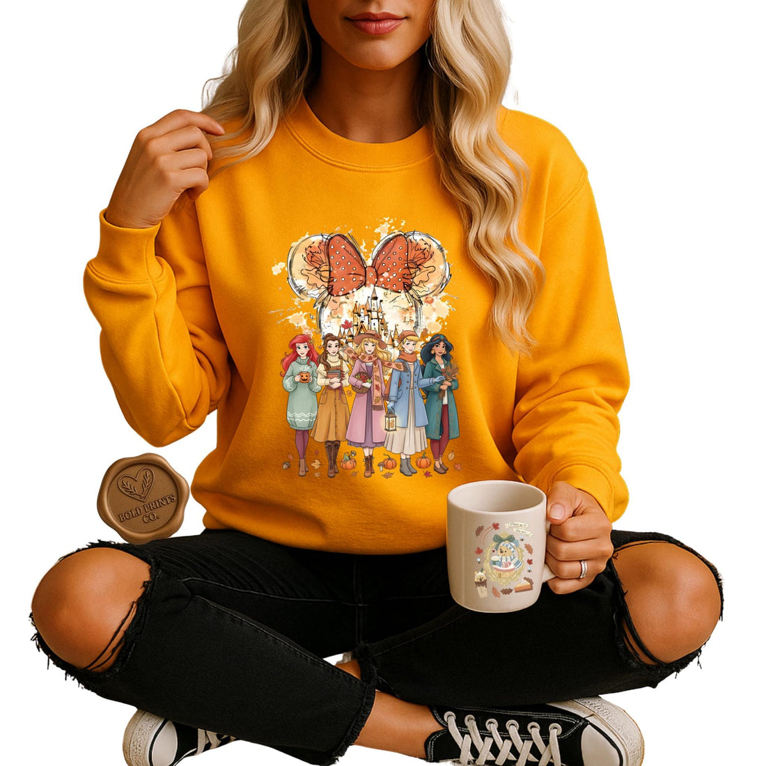 Woman in a mustard yellow Disney Princess-inspired fall sweatshirt holding a mug