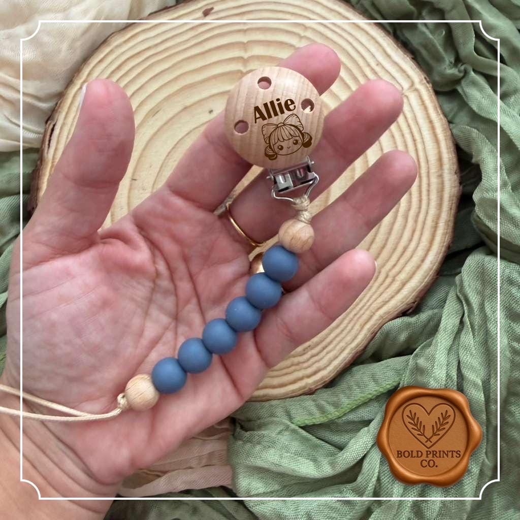 Navy and cream pacifier clip with an engraved wooden name disc