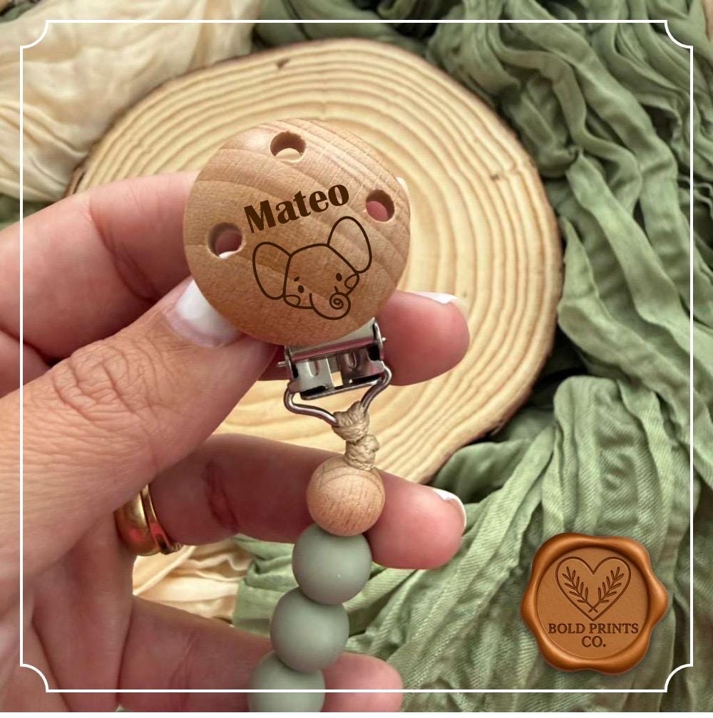 Sage green pacifier clip with a laser engraved name disc