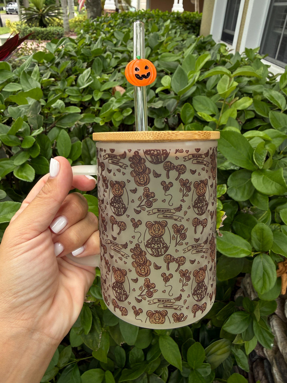 Halloween frosted glass cup with pumpkin straw held in hand