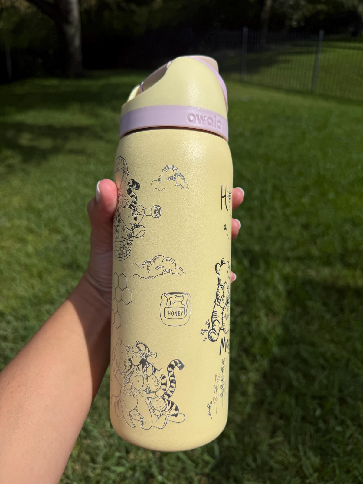 Back of a yellow Owala FreeSip showing more Hundred Acre Wood-inspired engraving