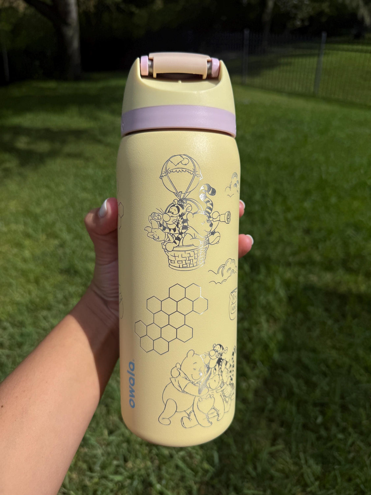 Side view of a yellow Owala with engraved Pooh and friends