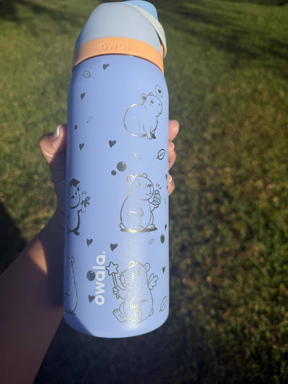 Side view of a periwinkle Owala with engraved capybaras and stars