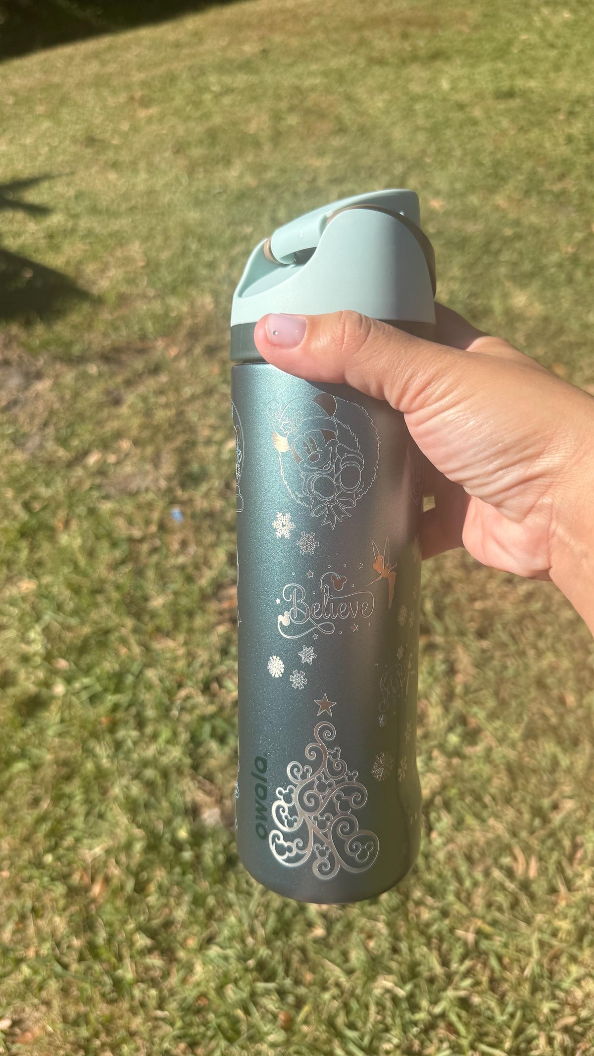 Side view of a slate teal Owala with engraved holiday artwork