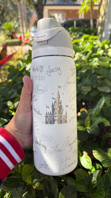 White Owala FreeSip laser engraved with a castle and Disney-inspired character signatures