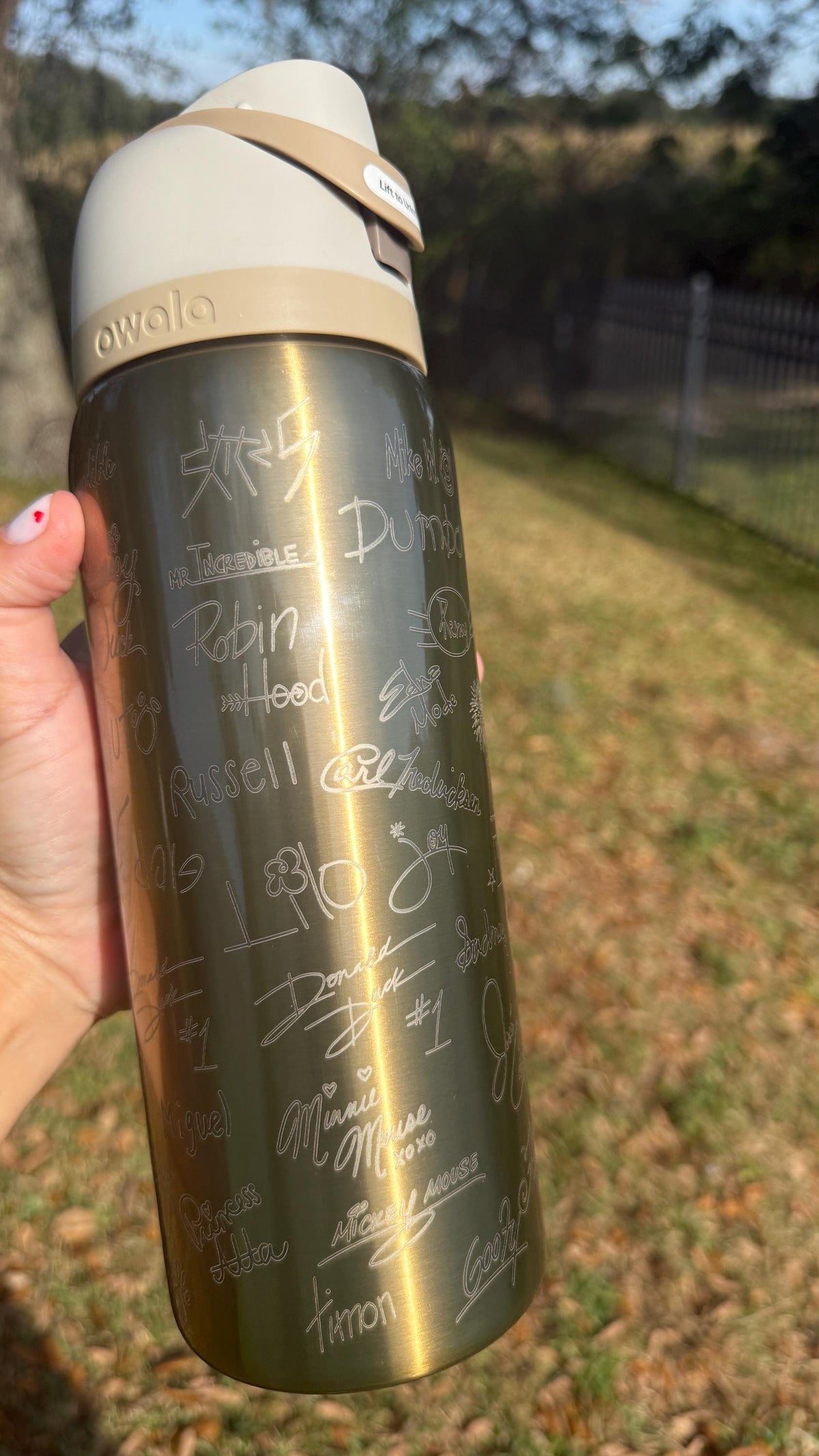 Side view of a gold Owala with engraved autograph-style signatures