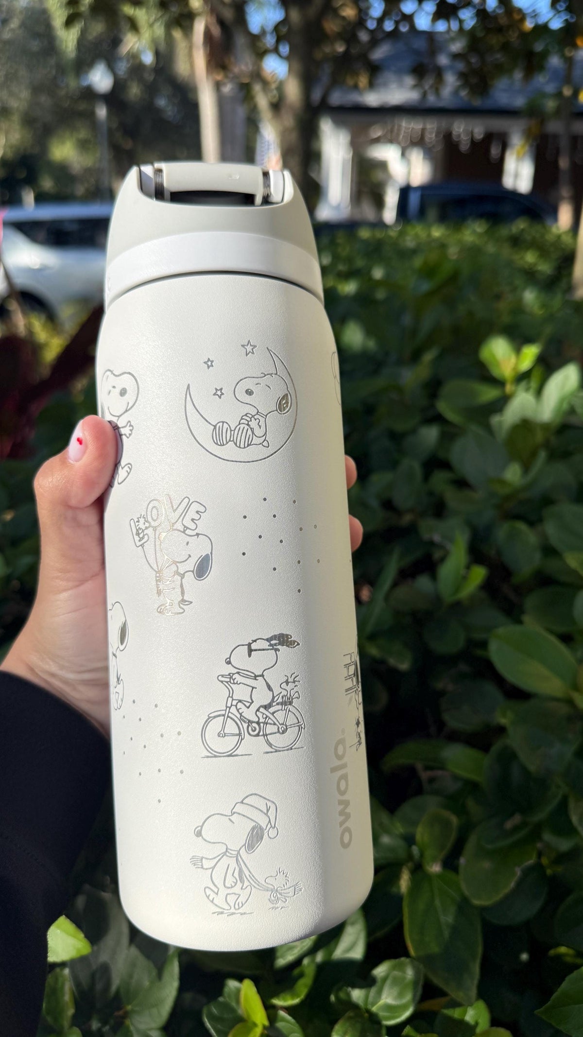 Close-up of Snoopy riding a bike engraved on a cream Owala