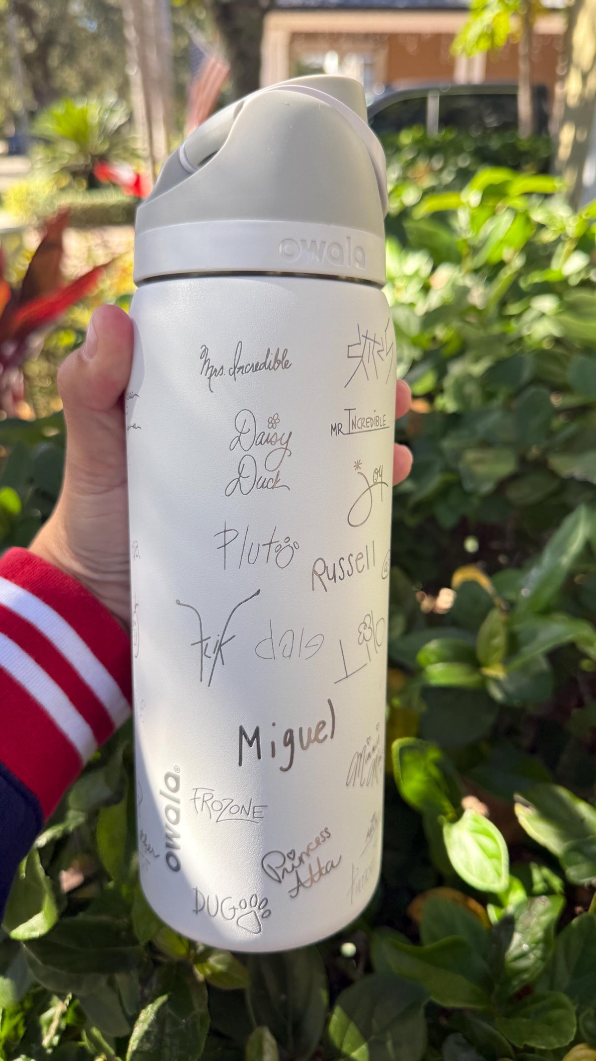 Back of a white Owala with signatures and the name Miguel engraved