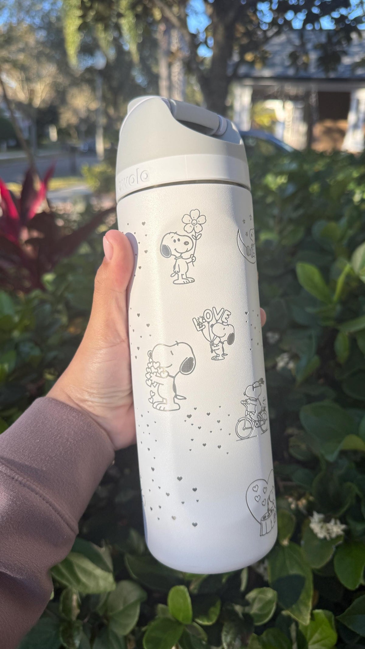 Close-up of Snoopy and hearts engraved on a white Owala
