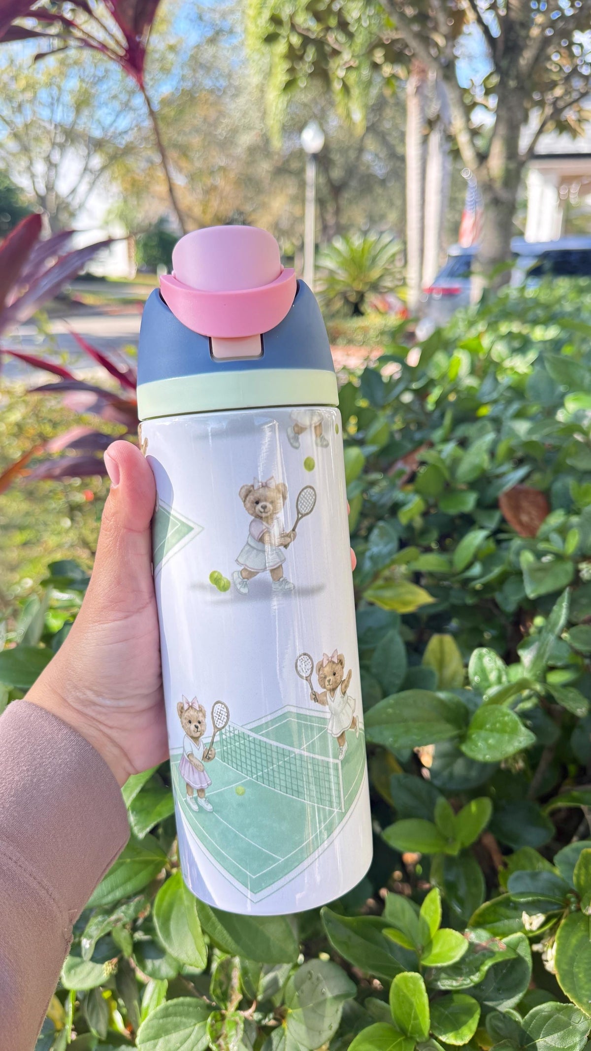 Tennis bear printed tumbler with pink lid, held outdoors