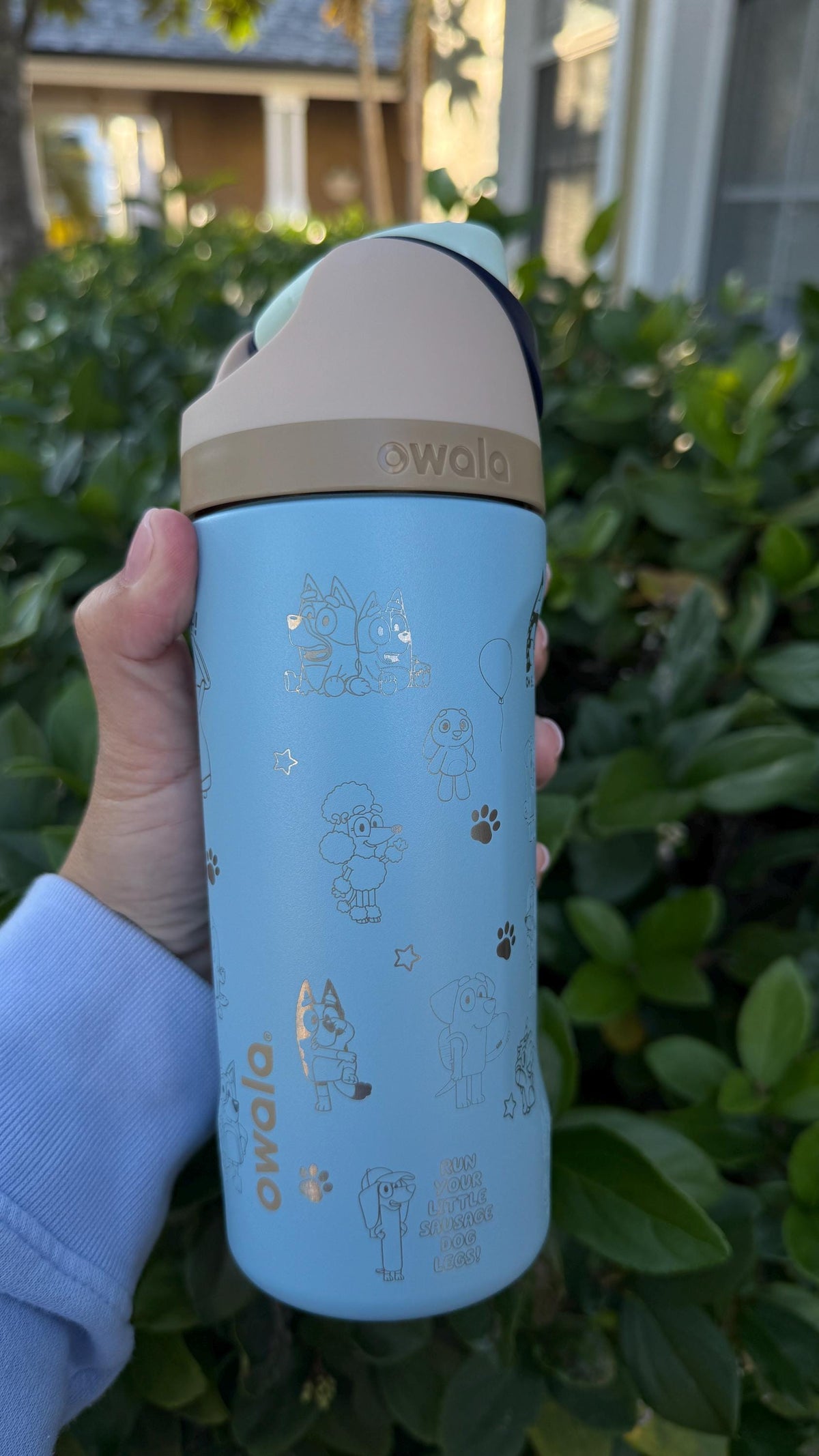 Side view of a light blue Owala with engraved Bluey-inspired characters