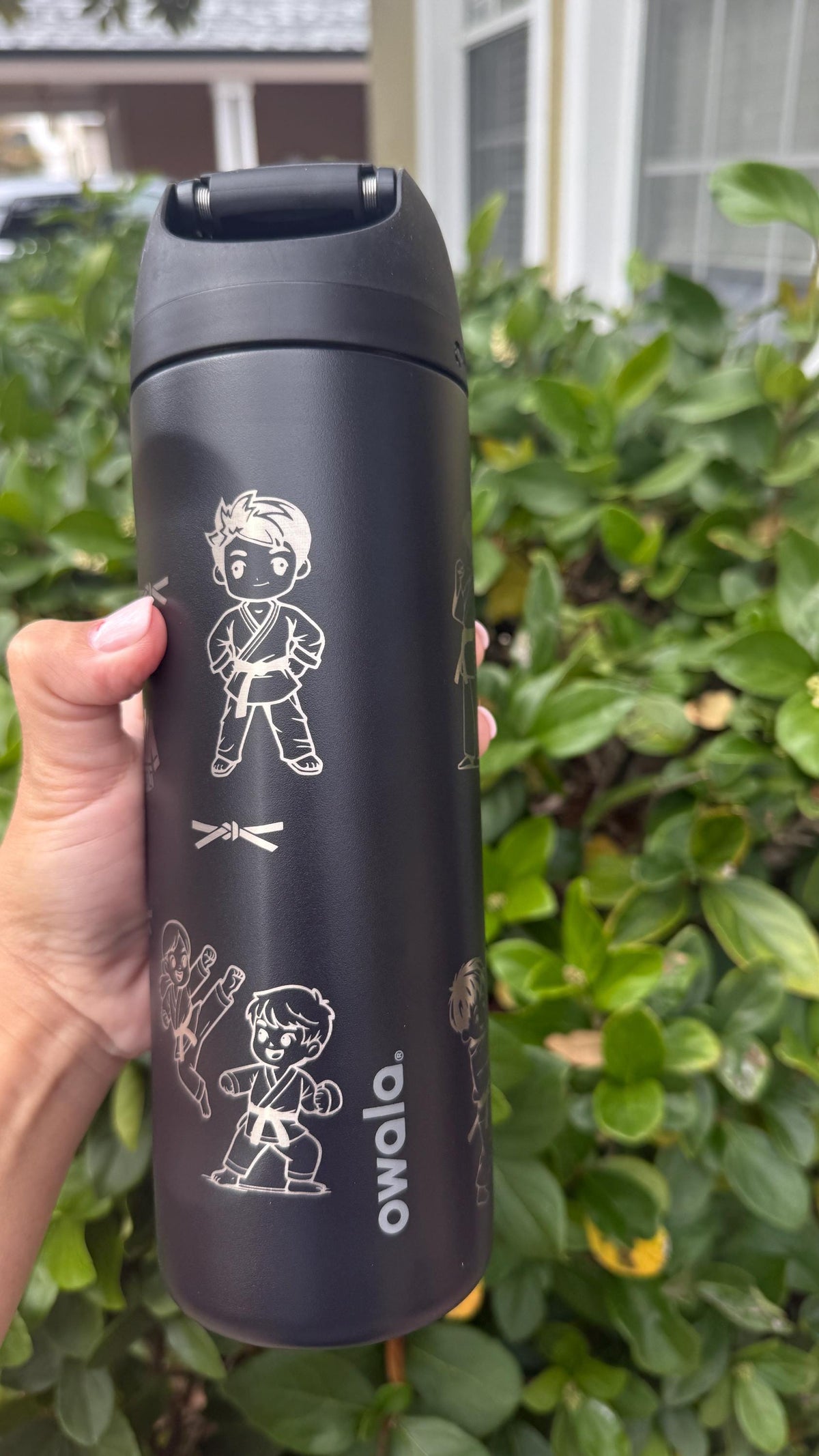 Side view of a black water bottle with engraved jiu-jitsu fighters