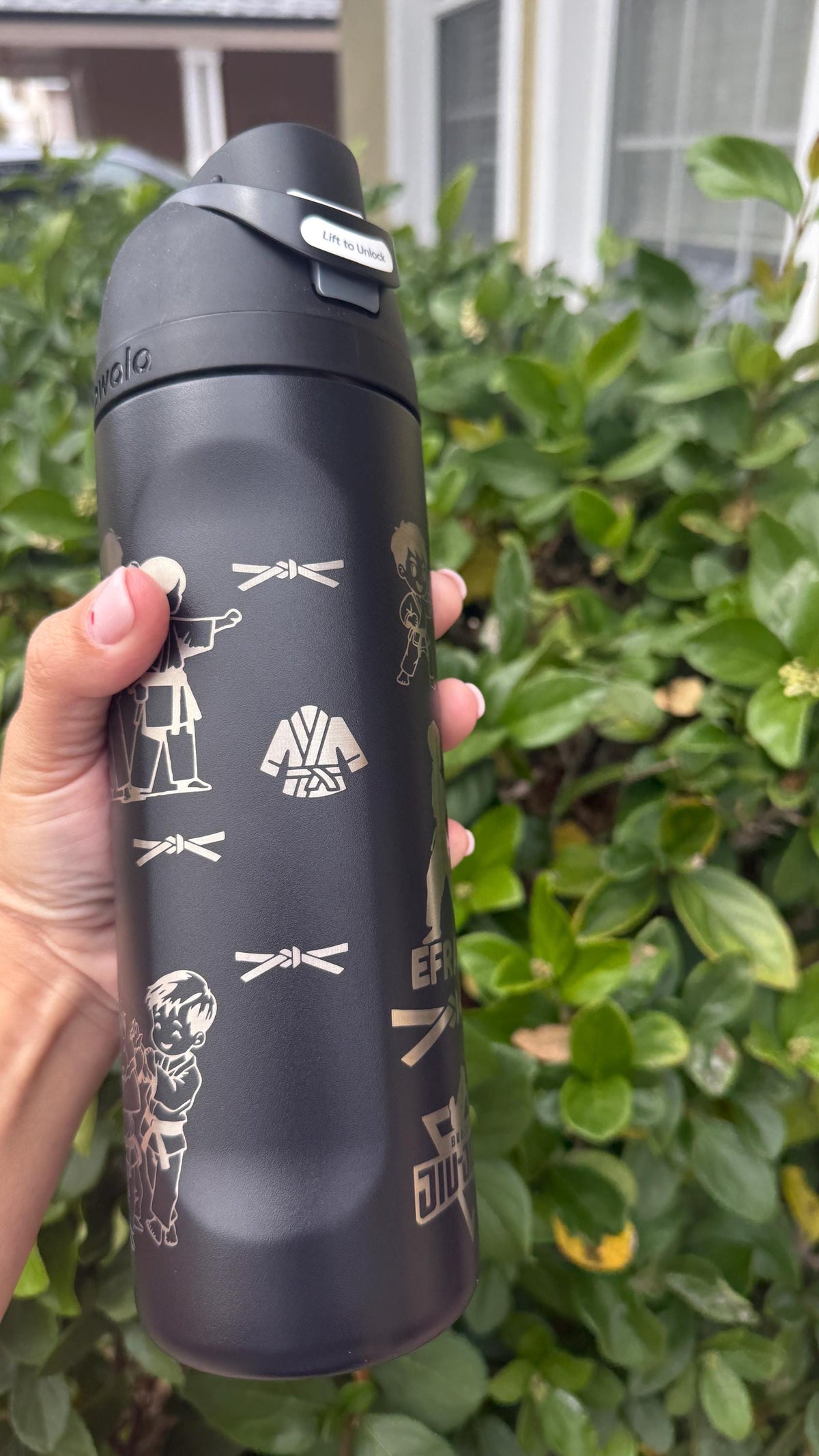 Close-up of jiu-jitsu belt and gi engraving on a black water bottle