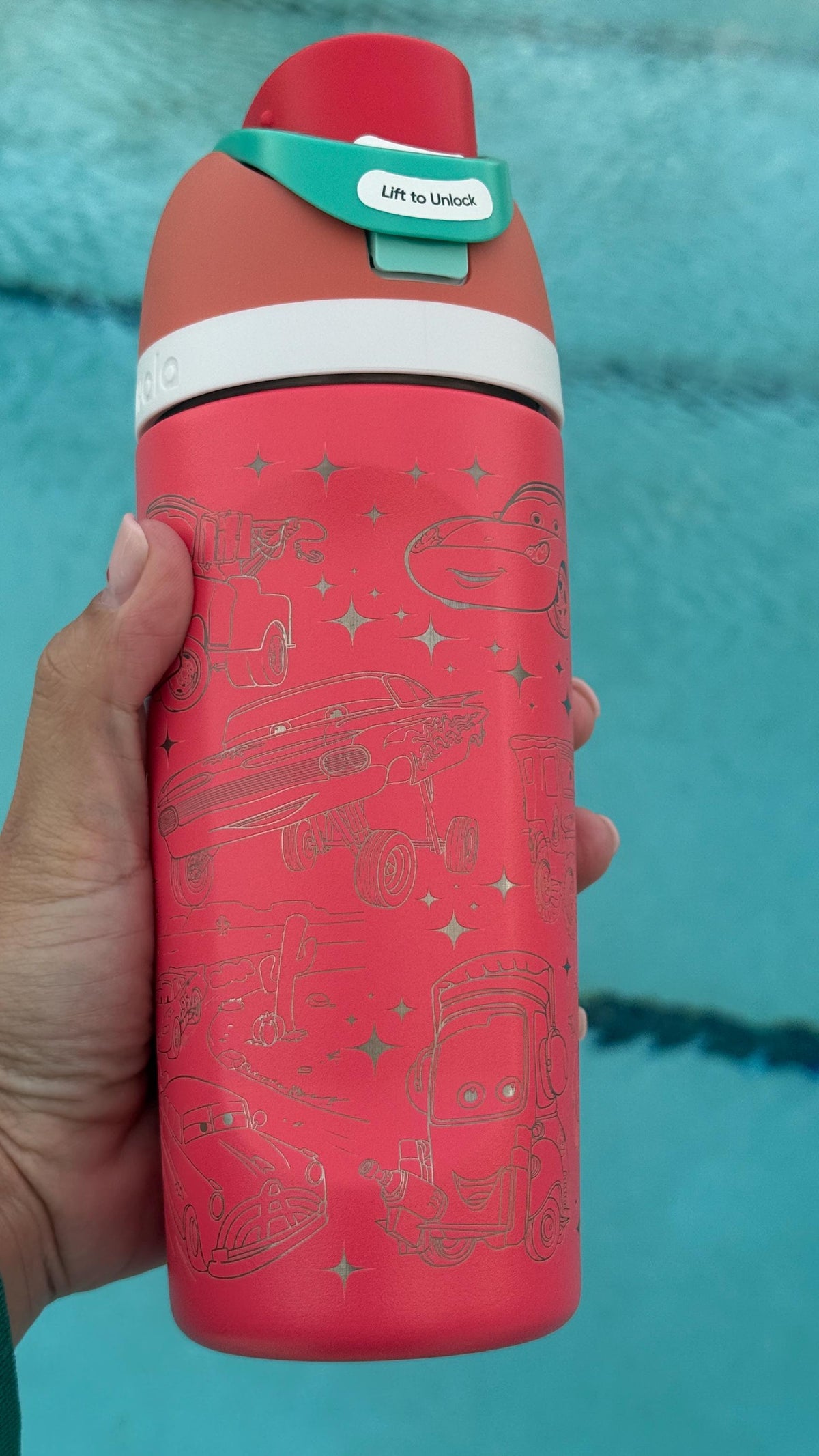 Red engraved Owala FreeSip held by a pool