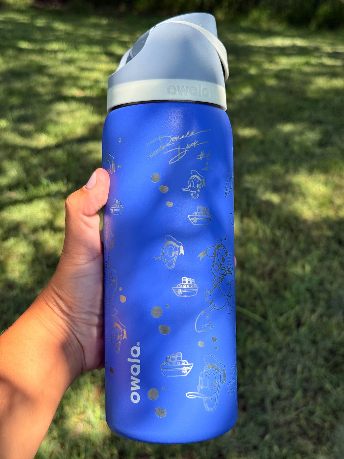 Side view of a blue engraved Owala FreeSip with Donald Duck artwork