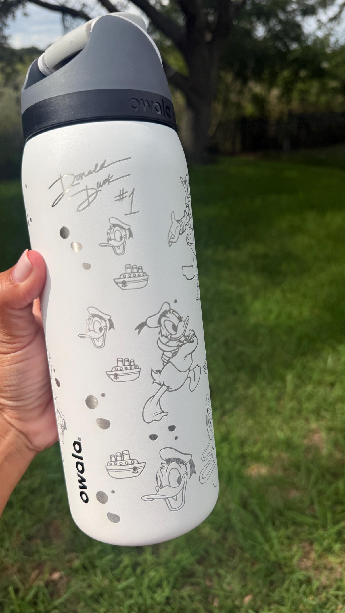 Side view of a white Owala bottle with engraved Donald Duck details