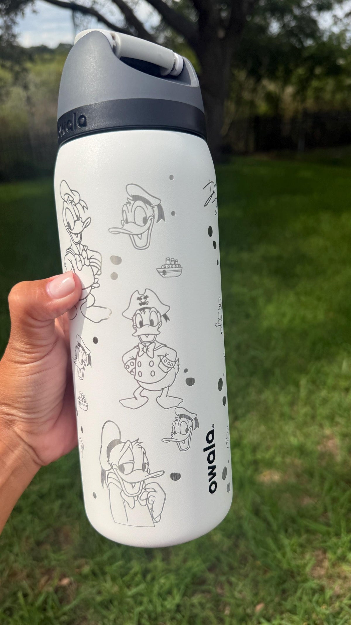 White engraved Owala FreeSip showing Donald Duck poses around the bottle