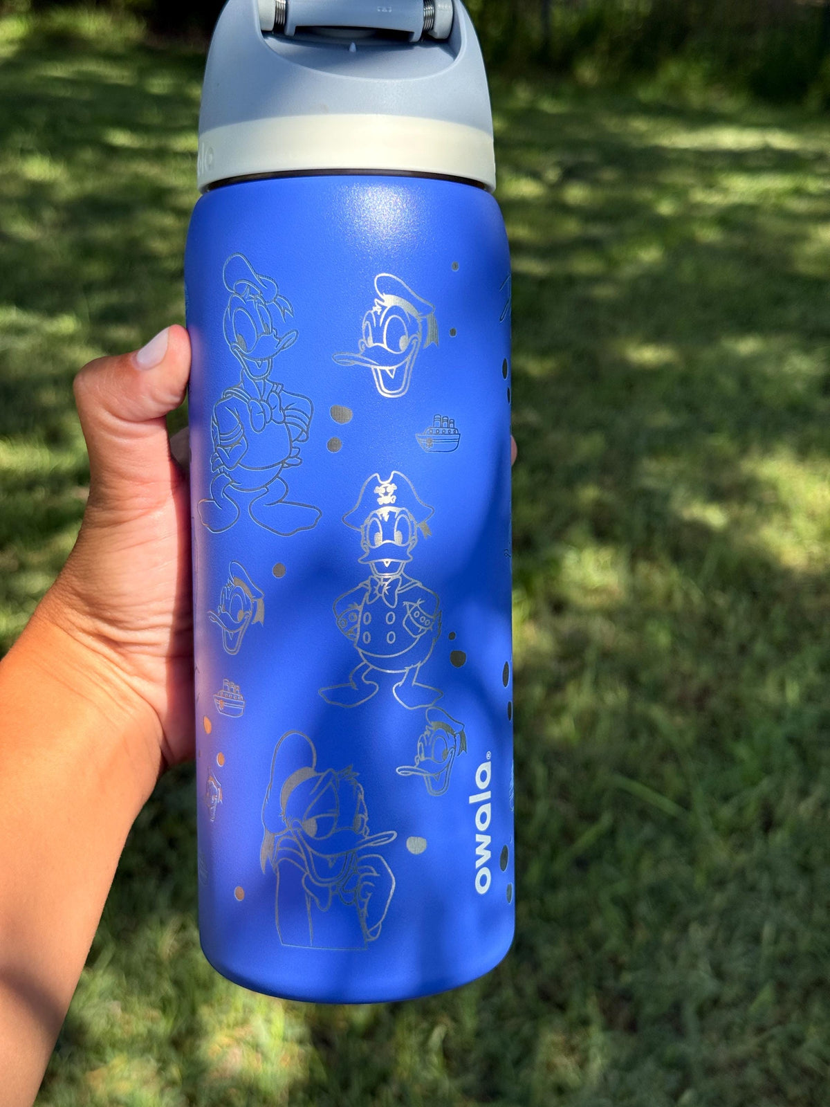 Blue Owala FreeSip with laser engraved Donald Duck design, held outdoors