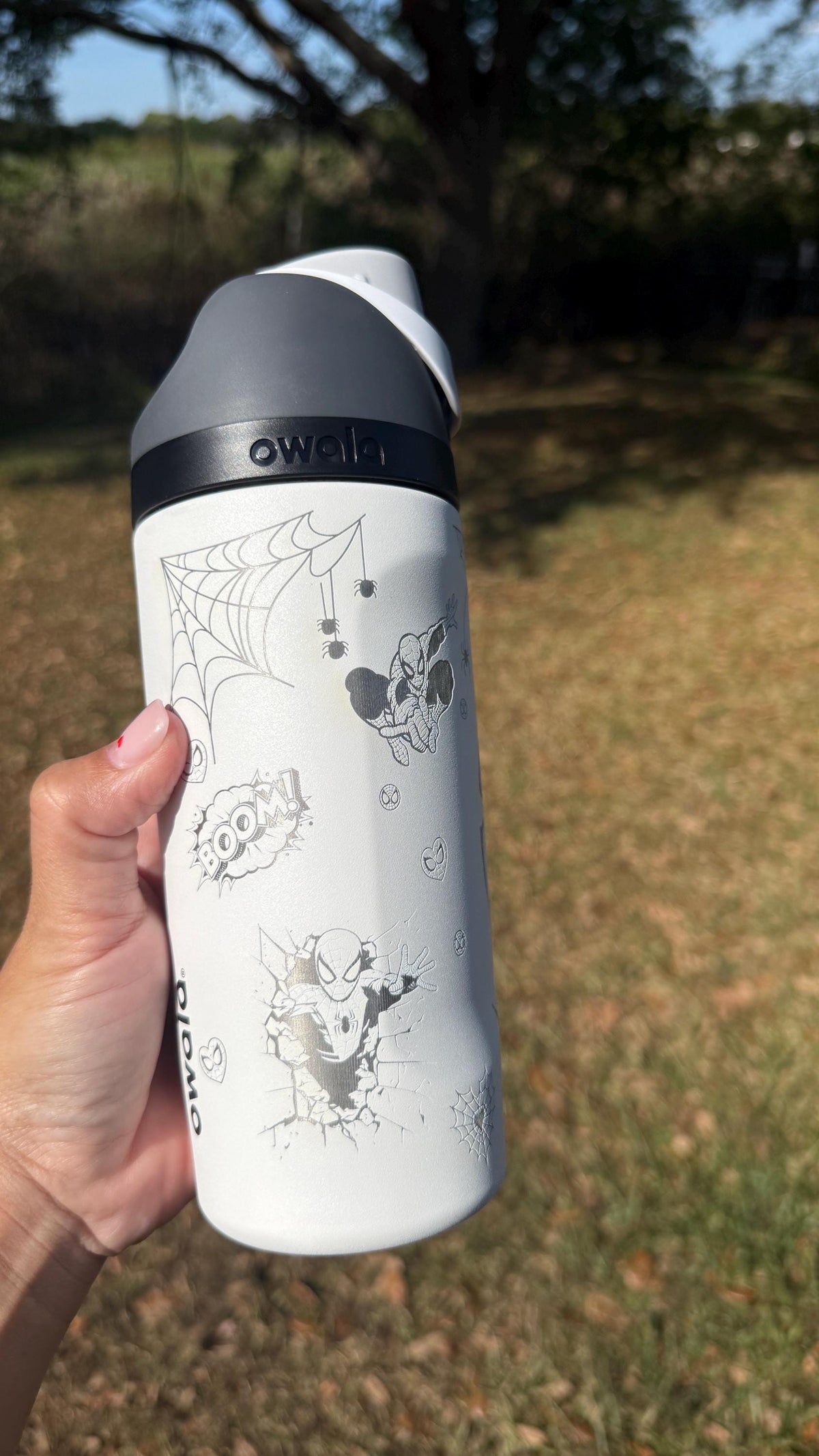 Side view of a white Owala with engraved Spider-Man artwork