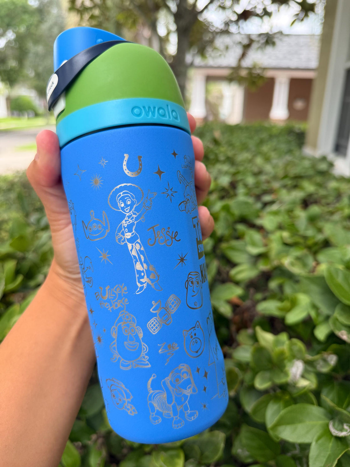 Side view of a blue Owala with engraved stars and toy characters