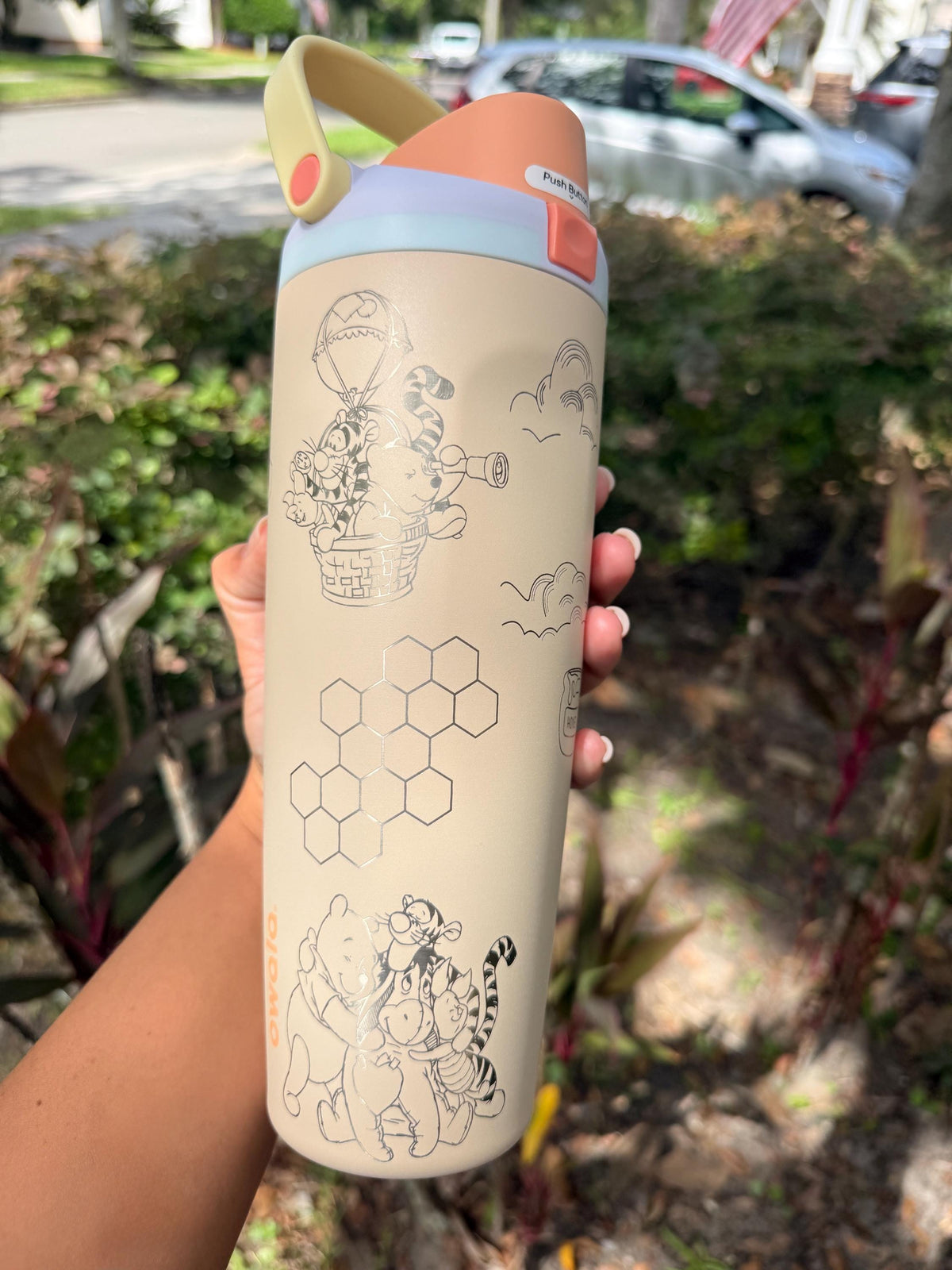 Cream engraved Winnie the Pooh Owala Sway held outdoors