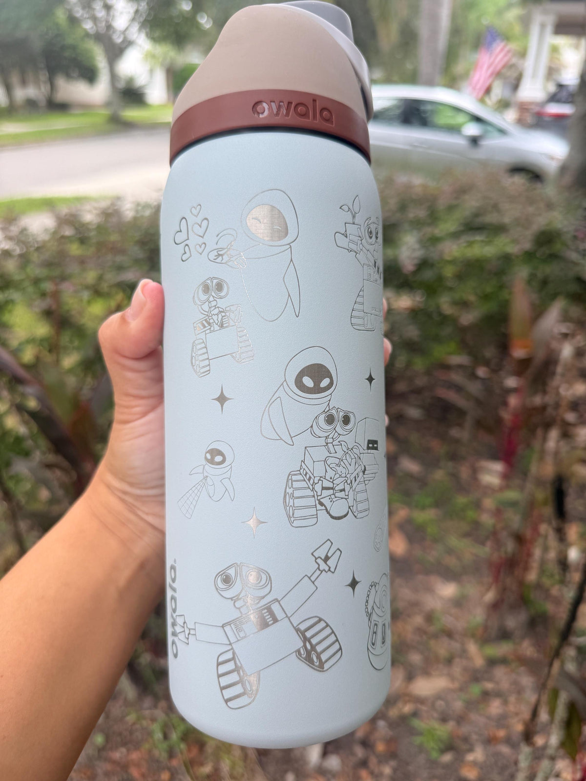 Light blue engraved Owala water bottle held outdoors