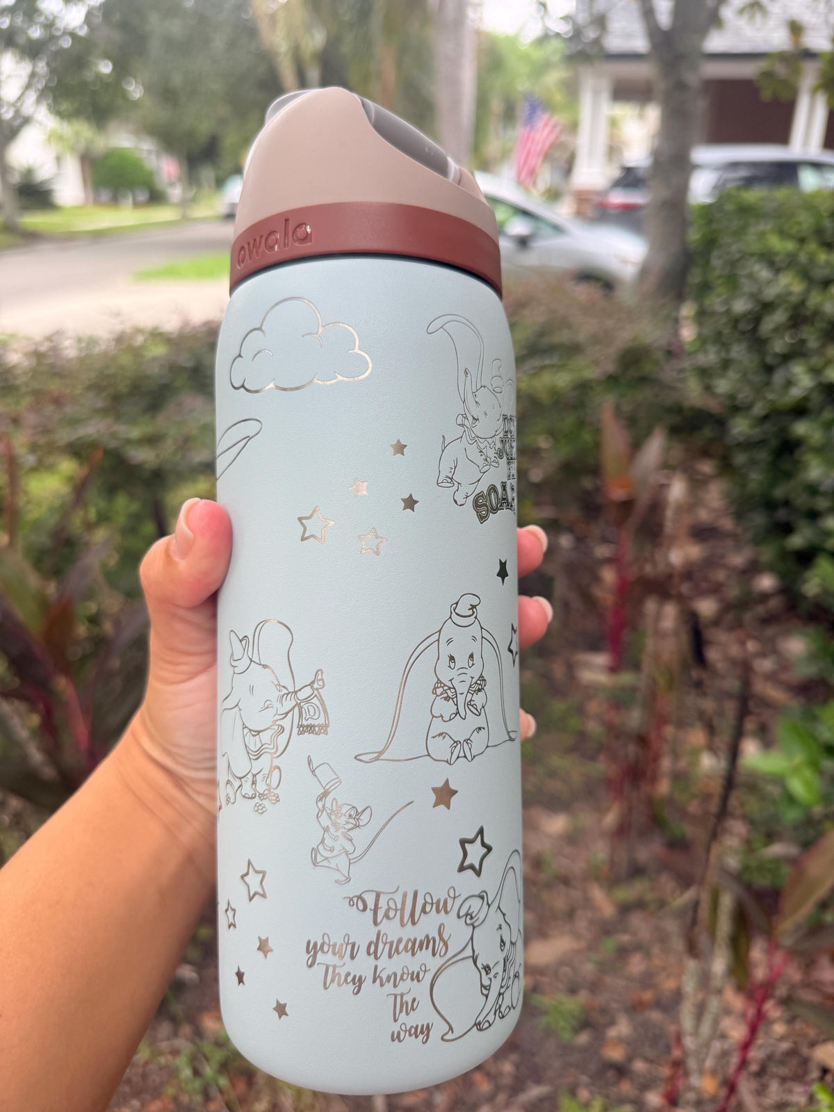 Side view of a light blue Owala with engraved Dumbo and circus stars